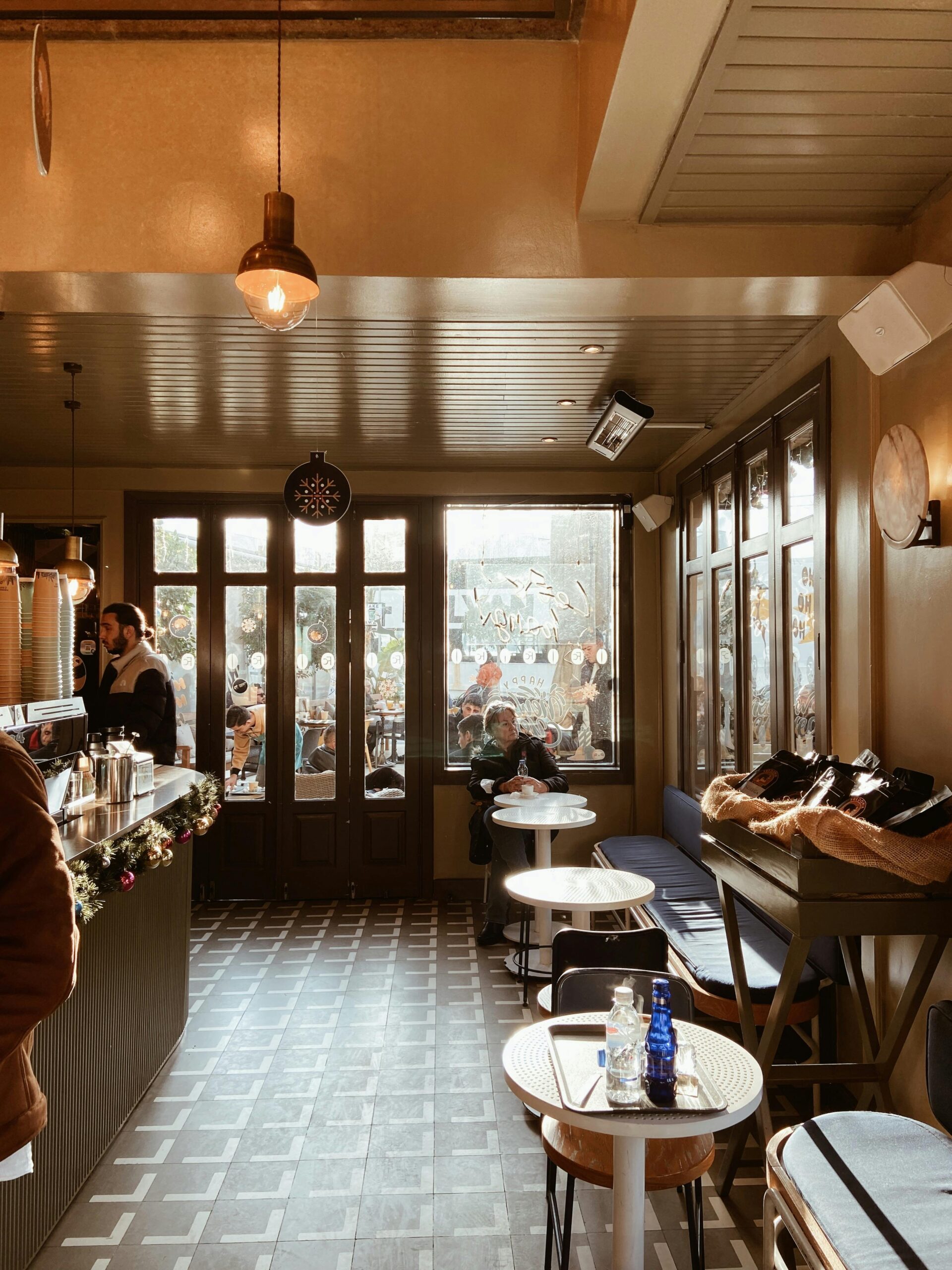 Warm and inviting café interior with wooden furniture, large windows, and soft lighting.