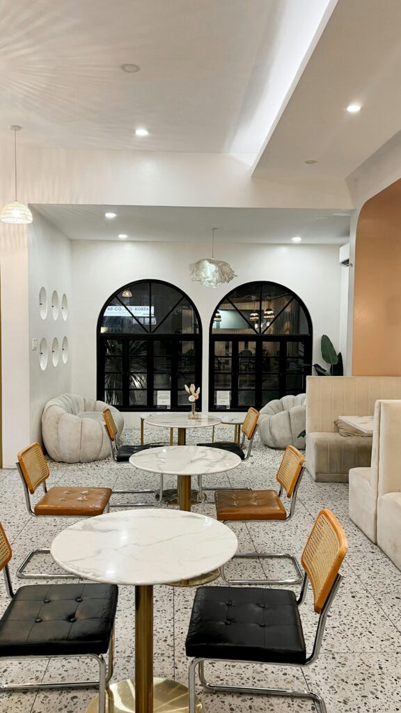 Elegant modern cafe interior with marble tables, arch windows, and stylish seating for a cozy ambiance.