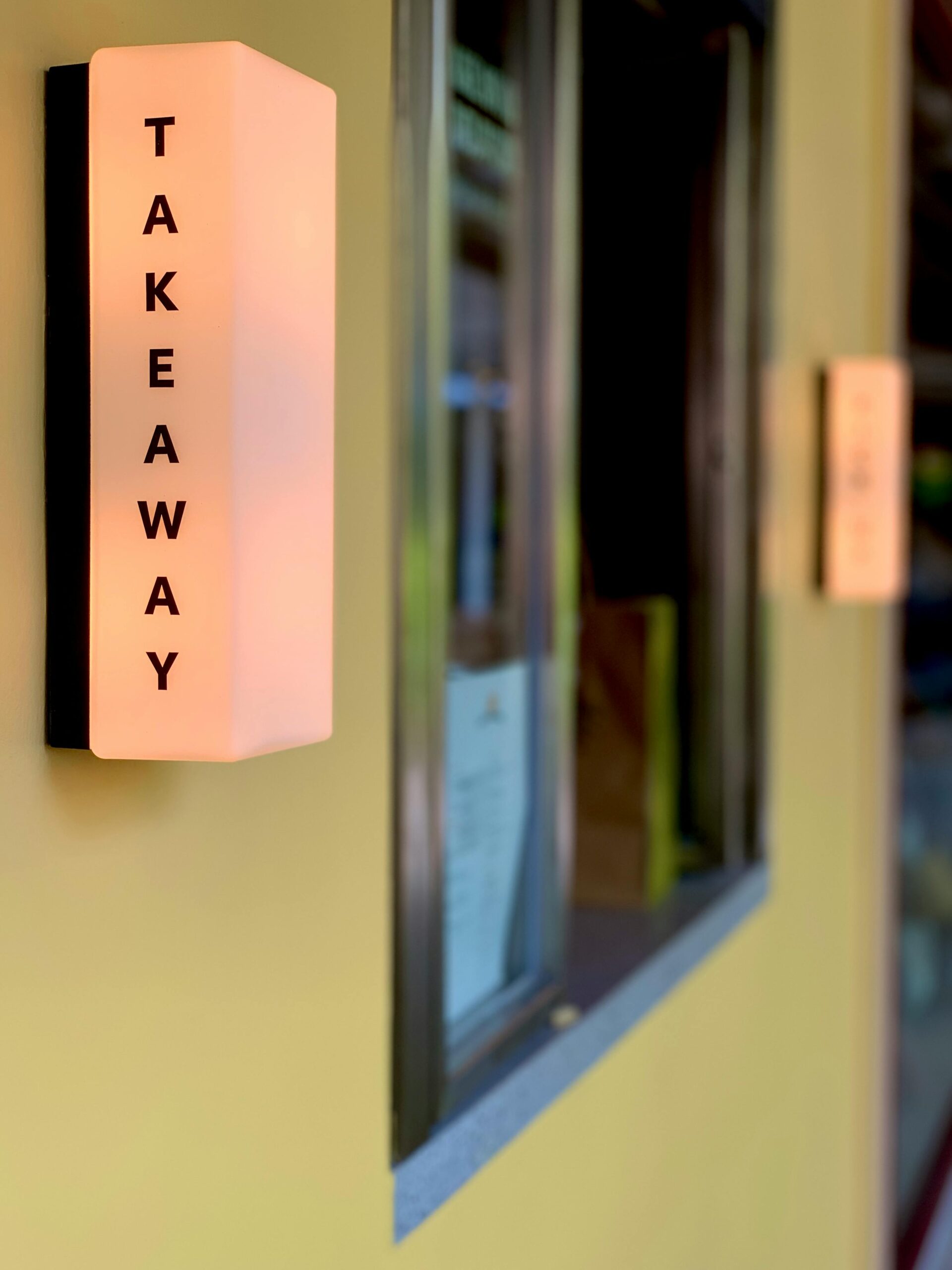 Bright outdoor takeaway sign on restaurant wall, ideal for modern dining concepts.