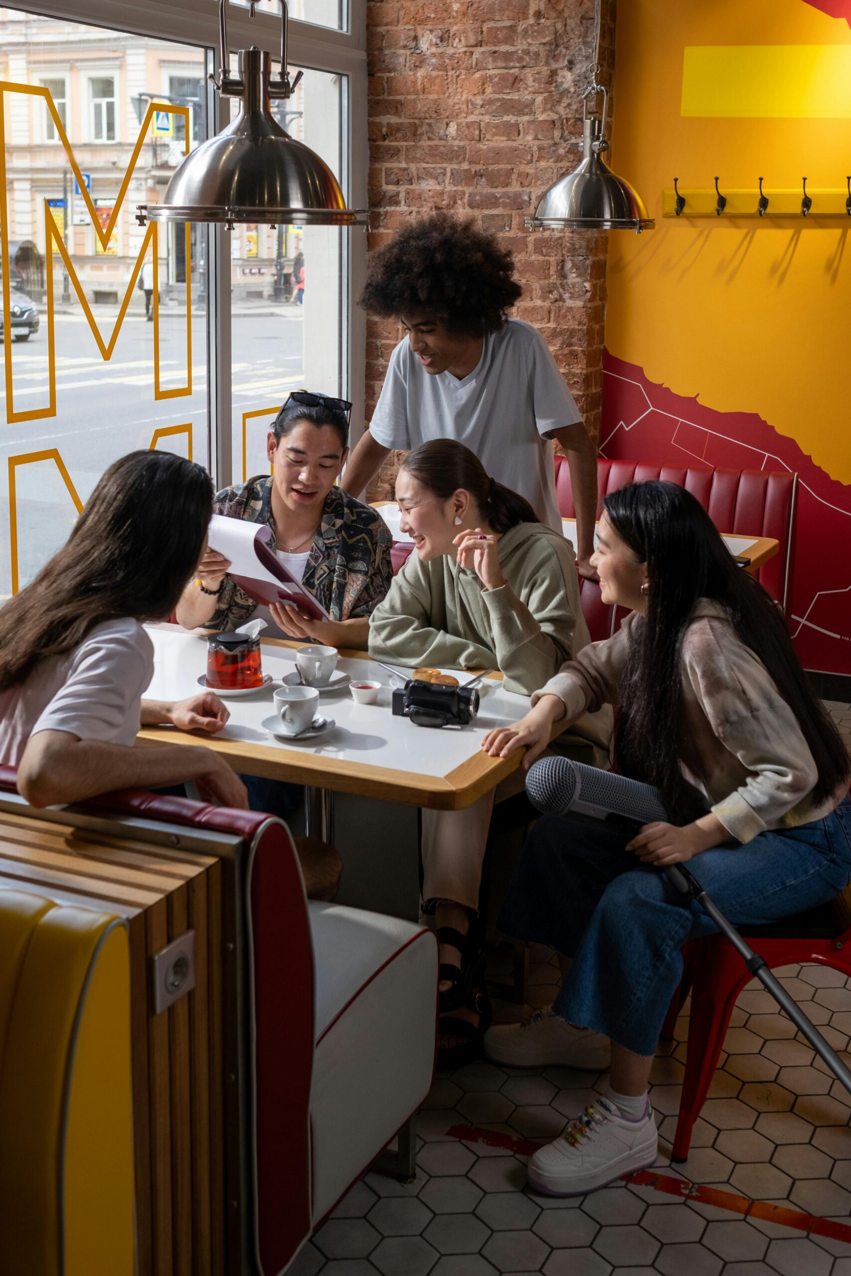 Group of young adults enjoying coffee and conversation in a lively, modern café setting.